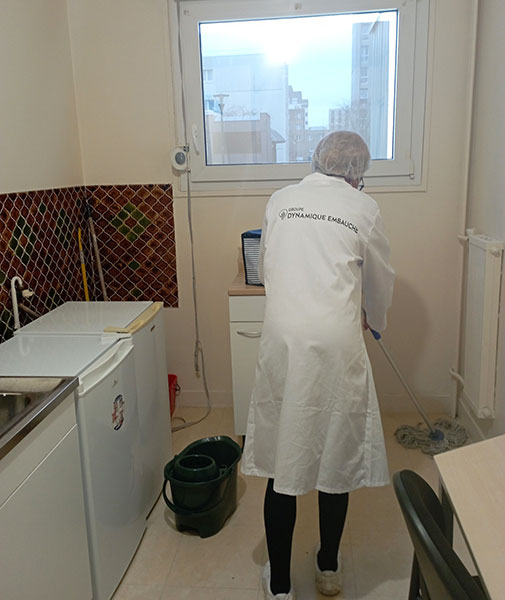 Photo d'une femme de ménage nettoyant le sol d'une cuisine avec un balais à frange