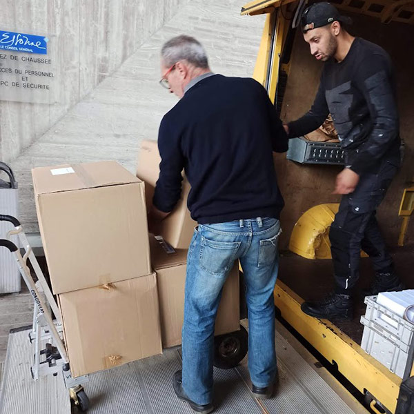 Photo de deux hommes installant des cartons sur un chariot dans un bâtiment du conseil général de l'Essonne