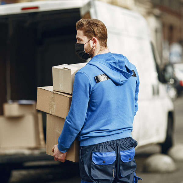 Photo d'un livreur transportant une pile de cartons vers une camionnette