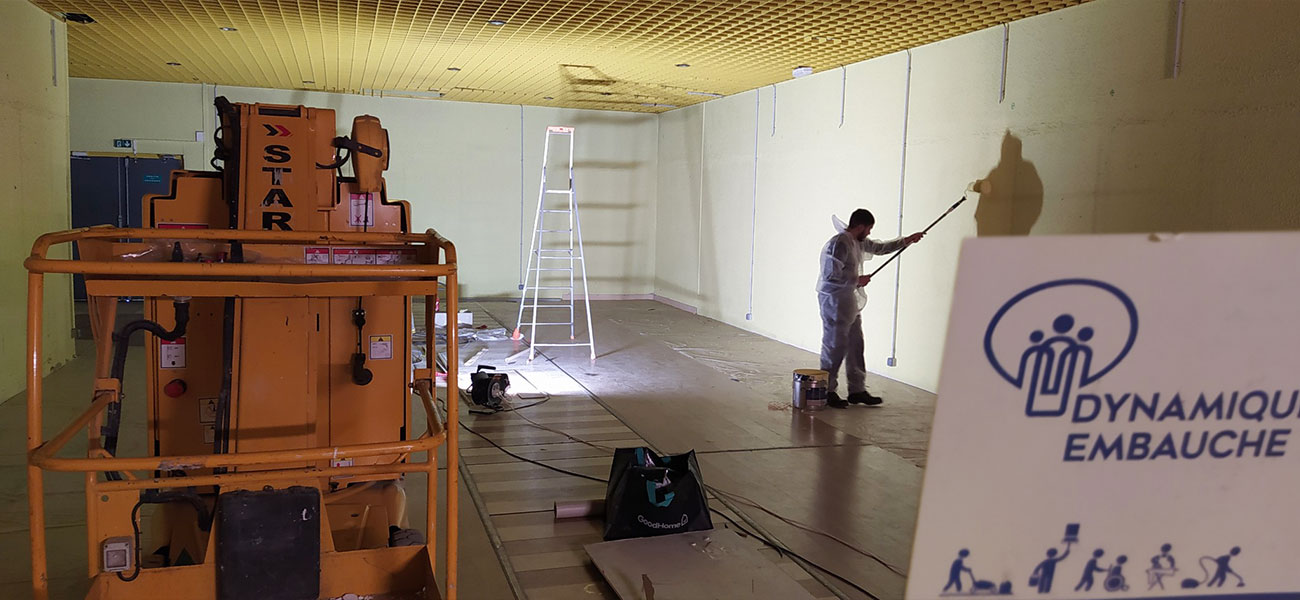 Photo d'un de nos peintres peignant au rouleau les murs d'un entrepôt en cours de rénovation